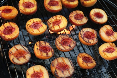 Photo of Modern grill with tasty cut peaches, closeup