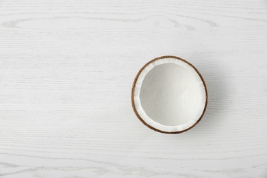 Photo of Half of coconut on white wooden background, top view. Space for text
