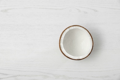 Half of coconut on white wooden background, top view. Space for text