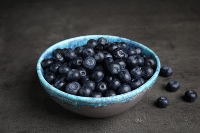 Bowl of tasty blueberries on grey table