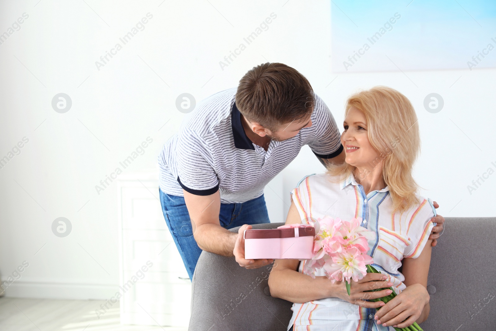 Photo of Young man congratulating his mature mom at home, space for text. Happy Mother's Day