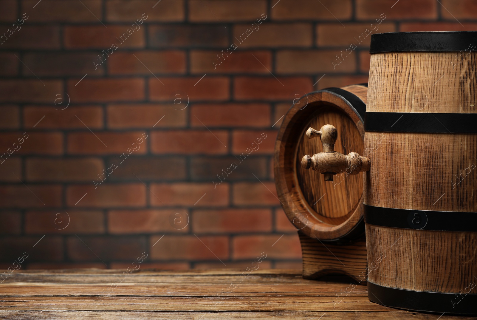 Photo of Wooden barrels on table near brick wall, space for text