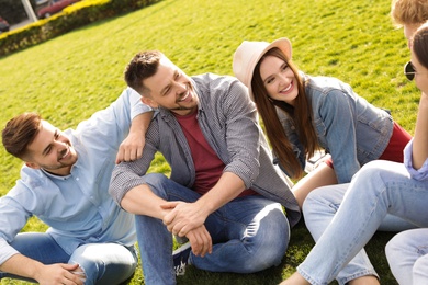 Photo of Happy people spending time together on green grass in park