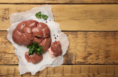 Photo of Fresh raw kidneys with seasonings on wooden table, top view. Space for text