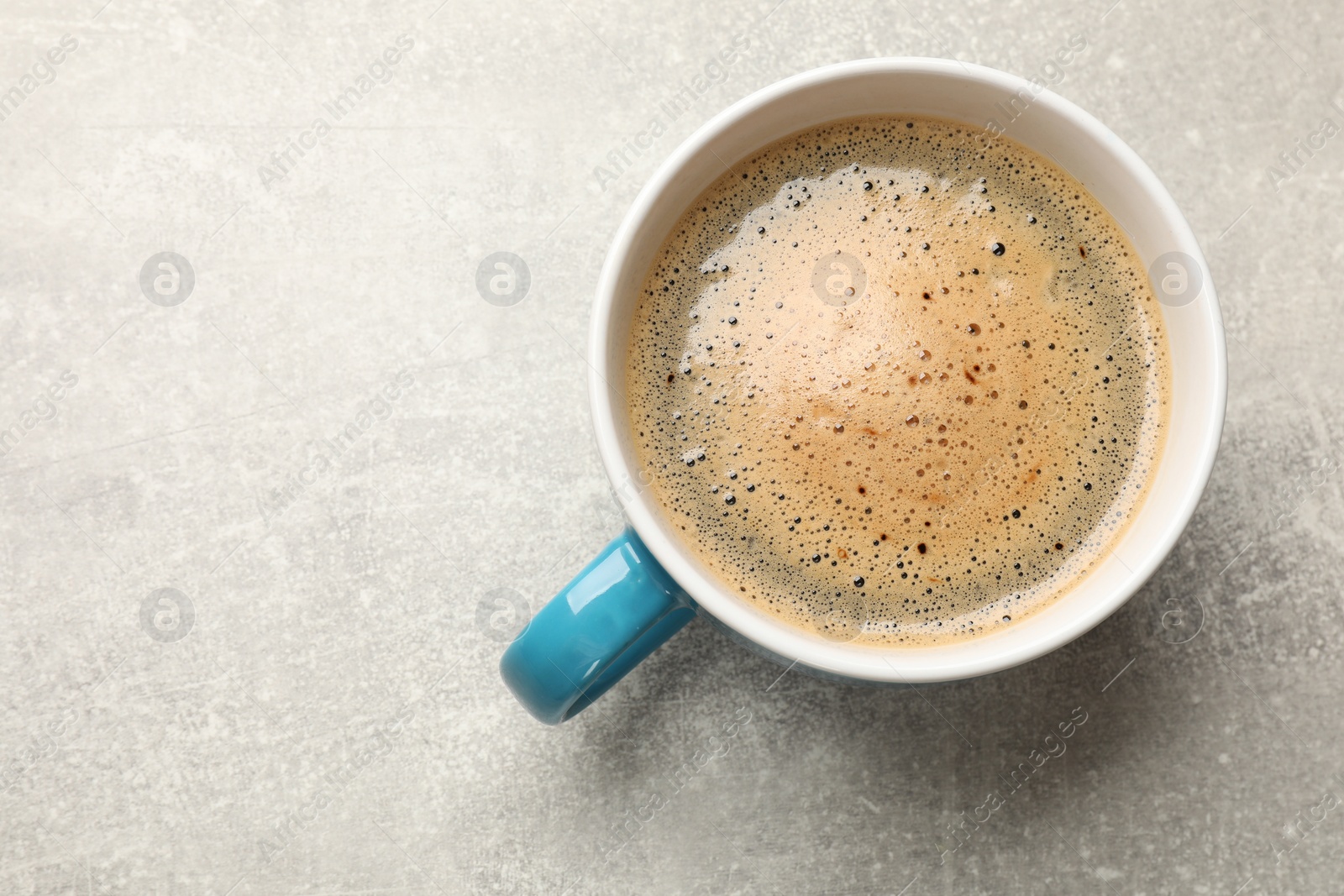 Photo of Cup of aromatic coffee on light grey table, top view. Space for text