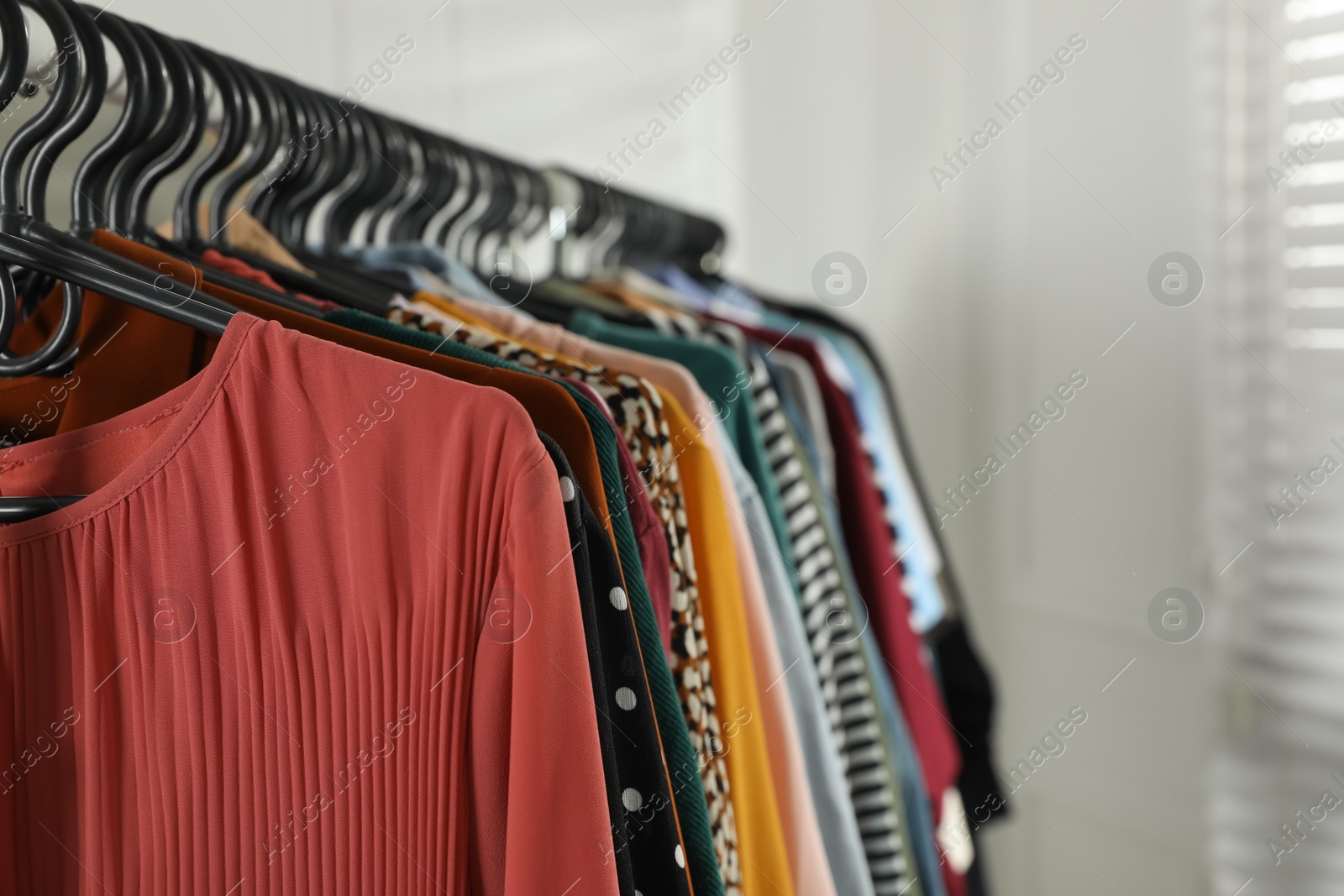 Photo of Rack with stylish clothes indoors, closeup. Fast fashion