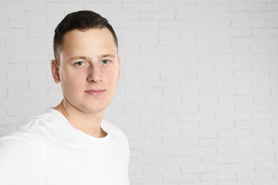 Photo of Handsome young man near white brick wall. Space for text