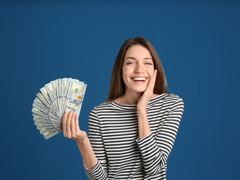 Photo of Happy young woman with cash money on blue background