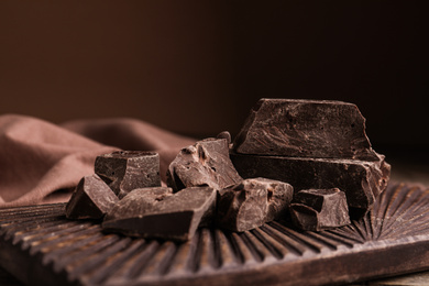 Pieces of tasty dark chocolate on wooden board