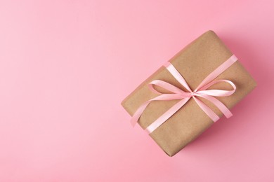 Photo of Beautiful gift box with bow on pink background, top view. Space for text