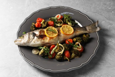 Photo of Baked fish with vegetables, rosemary and lemon on grey textured table