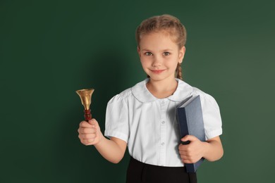 Pupil with school bell near green chalkboard