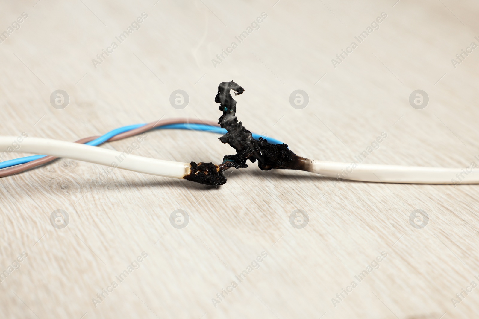 Photo of Burnt wires on wooden floor, closeup. Electrical short circuit