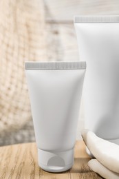 Tubes of hand cream and coconut pieces on wooden table, closeup