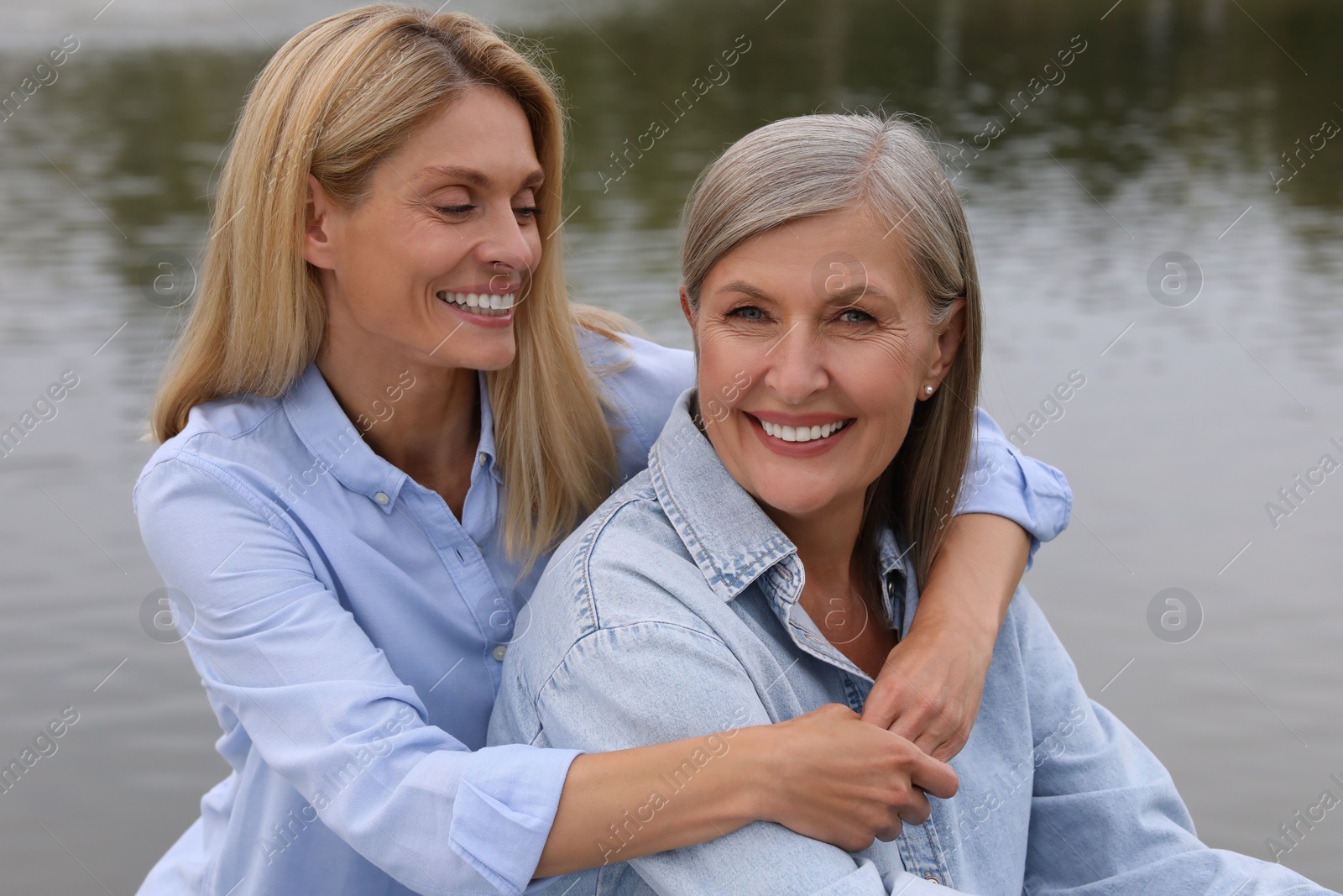 Photo of Happy mature mother and her daughter hugging near pond