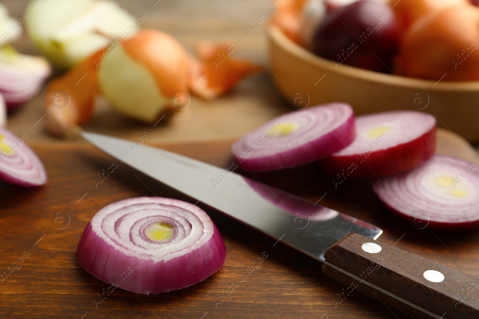 Photo of Sliced red onion and knife on wooden board, closeup