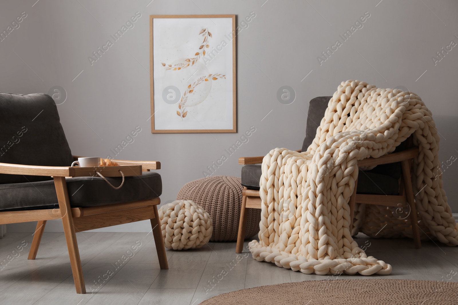 Photo of Soft chunky knit blanket on armchair in room. Interior design