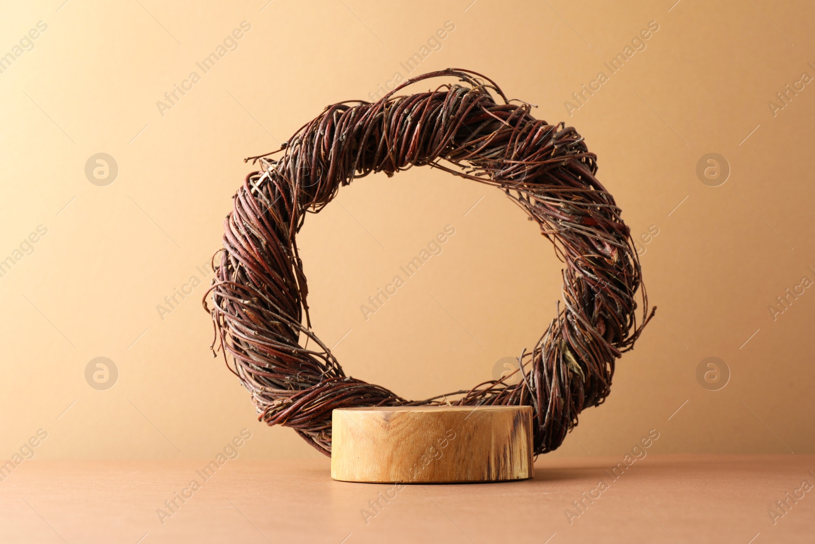 Photo of Presentation for product. Wooden podium and willow twig wreath on beige background