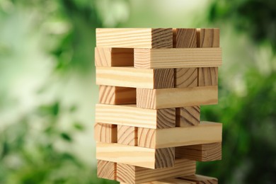 Photo of Jenga tower made of wooden blocks outdoors