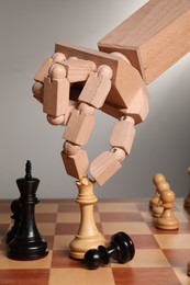 Photo of Robot moving chess piece on board against light grey background, closeup. Wooden hand representing artificial intelligence