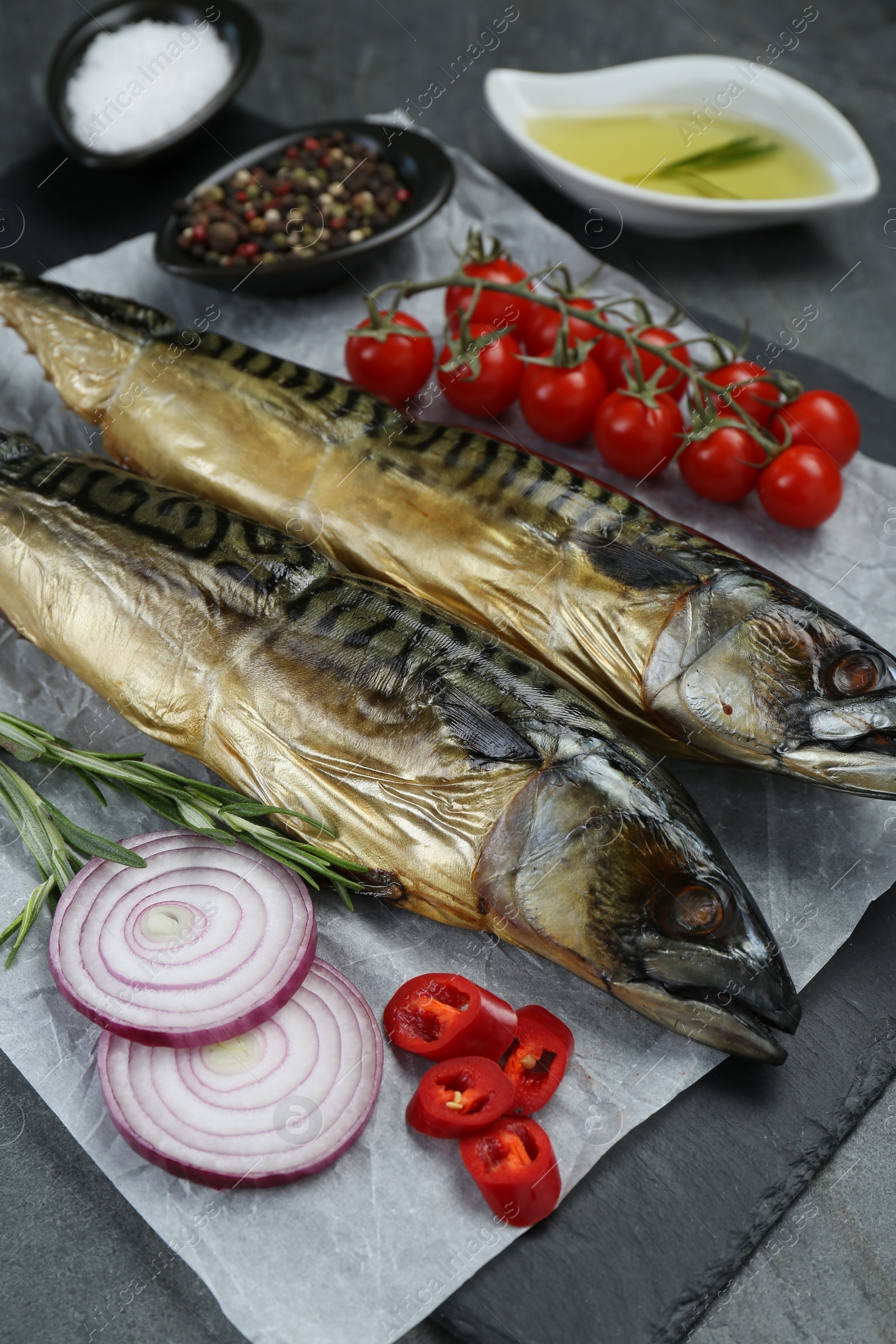 Photo of Delicious smoked mackerels and products on grey table, closeup