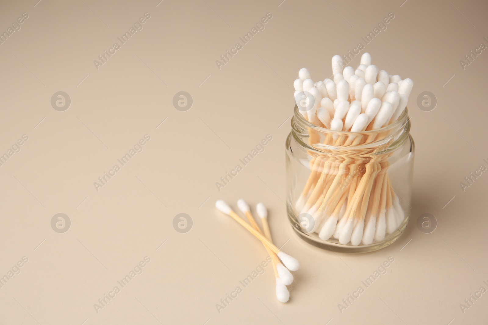 Photo of Jar and clean cotton buds on beige background. Space for text