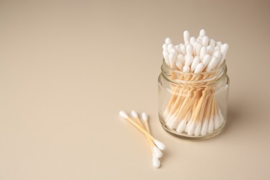 Jar and clean cotton buds on beige background. Space for text