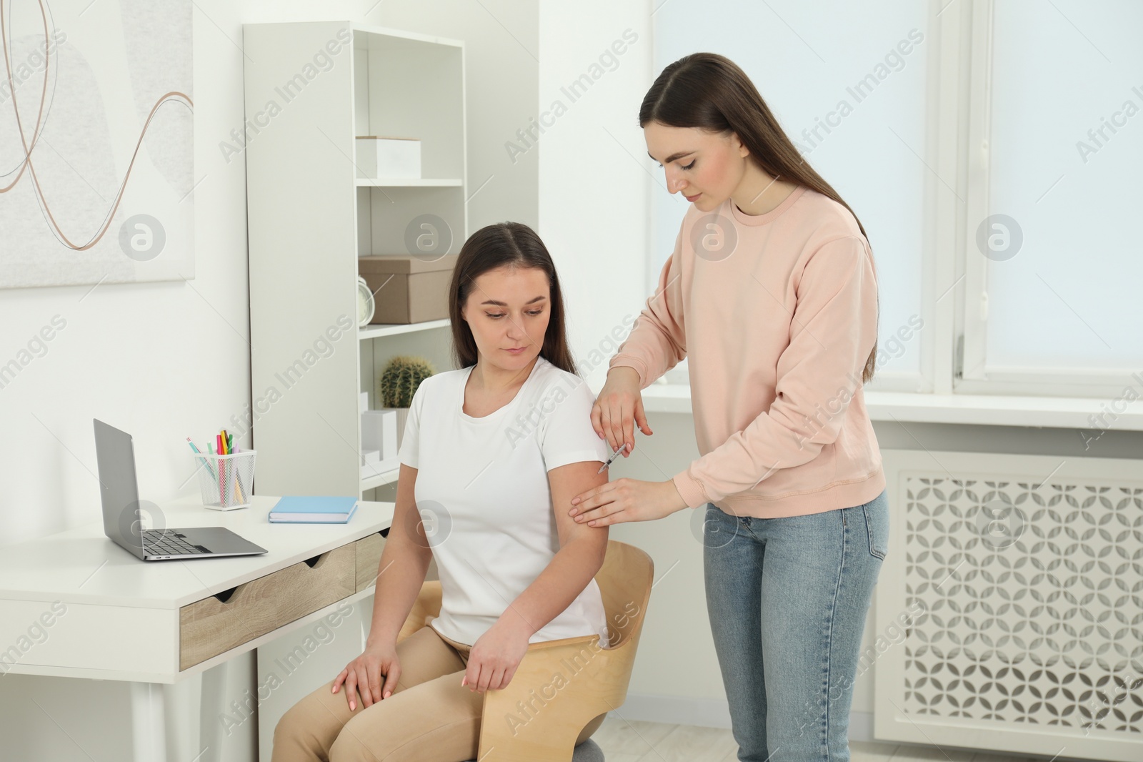 Photo of Woman giving insulin injection to her diabetic friend at home