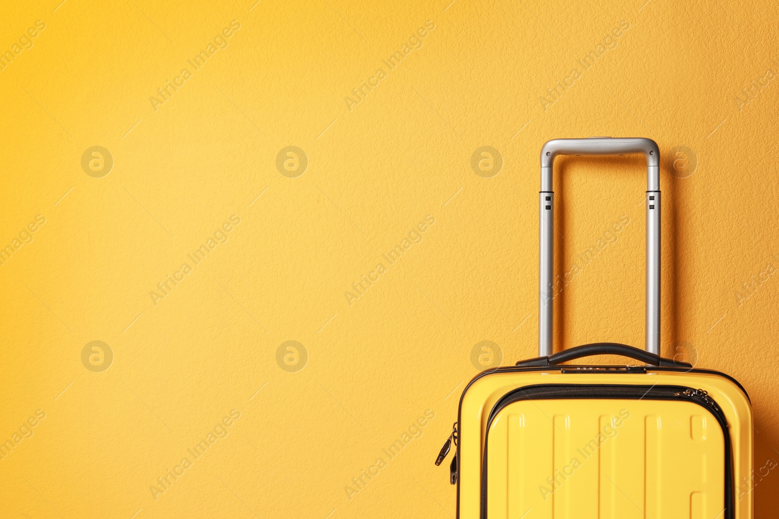 Photo of Bright yellow suitcase on color background