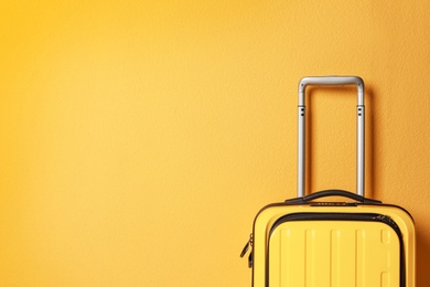 Photo of Bright yellow suitcase on color background