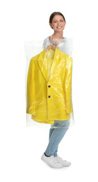 Photo of Young woman holding hanger with jacket in plastic bag on white background. Dry-cleaning service