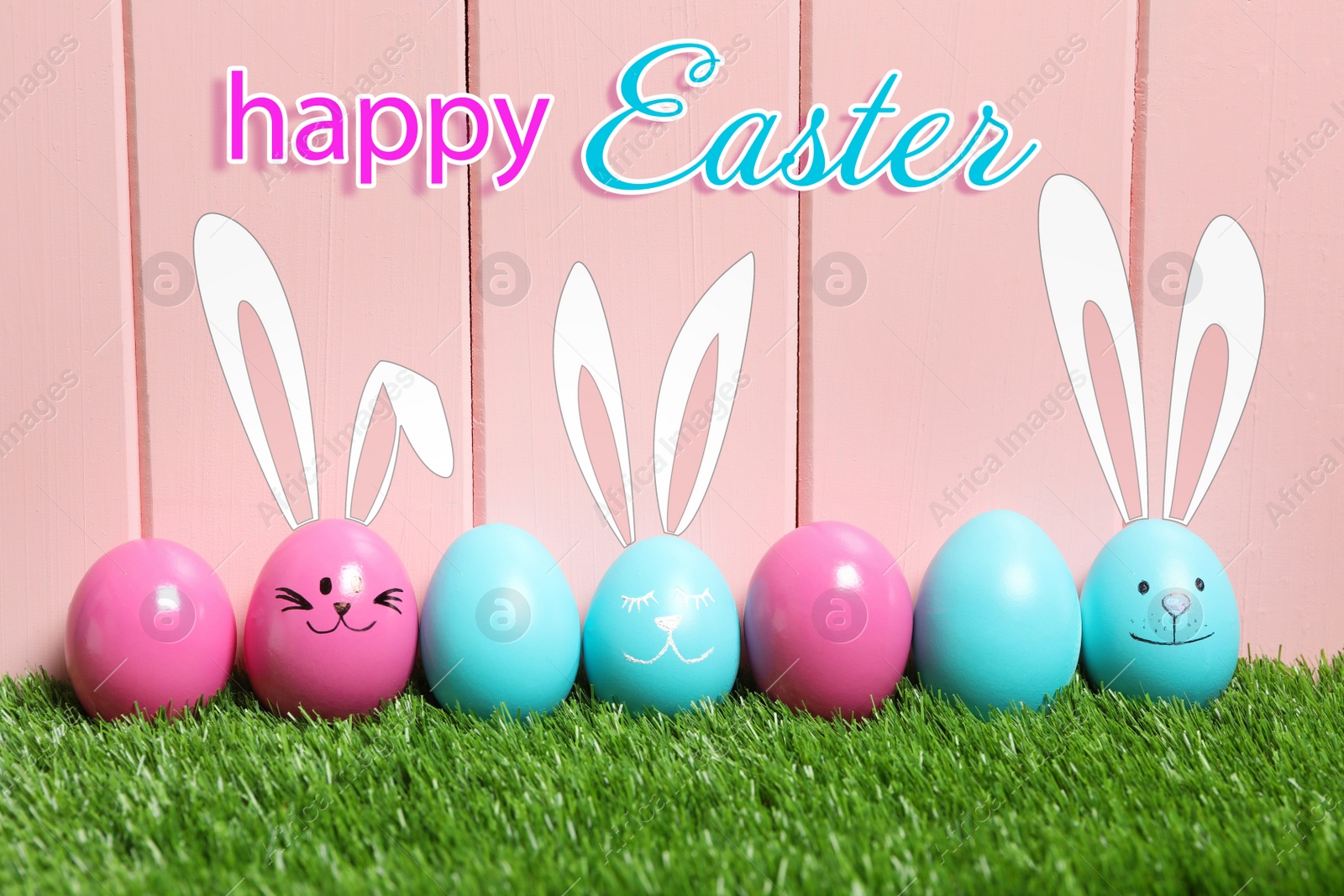 Image of Happy Easter. Several eggs with drawn faces and ears as bunnies among others on green grass against pink wooden background