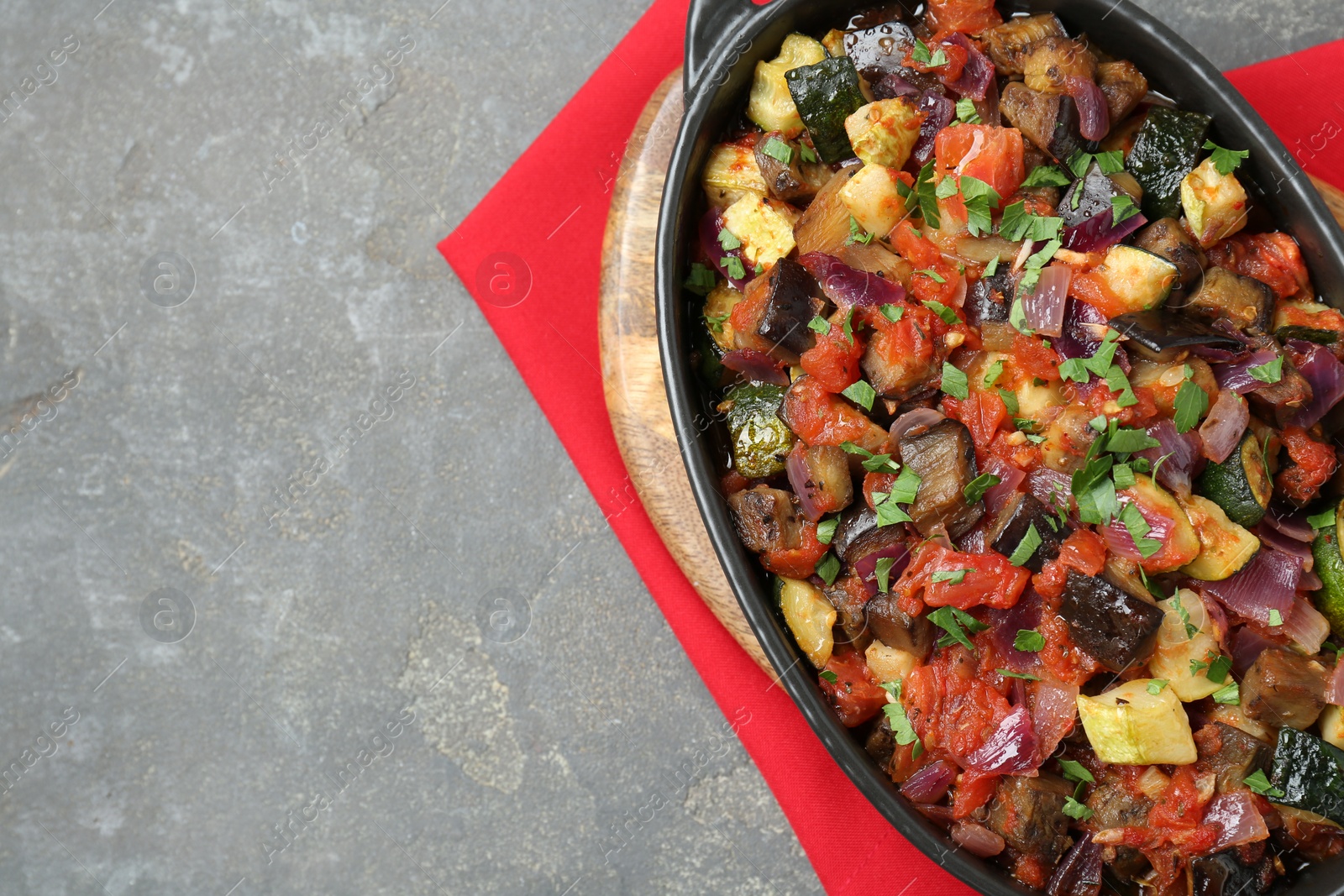 Photo of Dish with tasty ratatouille on grey textured table, top view. Space for text