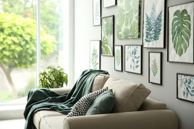 Photo of Beautiful artworks and comfortable couch in stylish room. Interior design