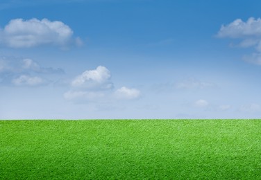 Image of Green grass under blue sky with clouds