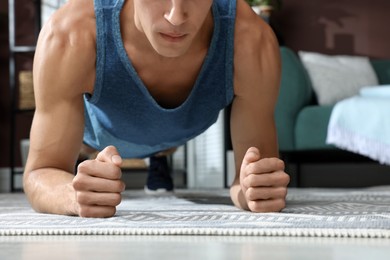 Photo of Man doing plank exercise on floor at home, closeup