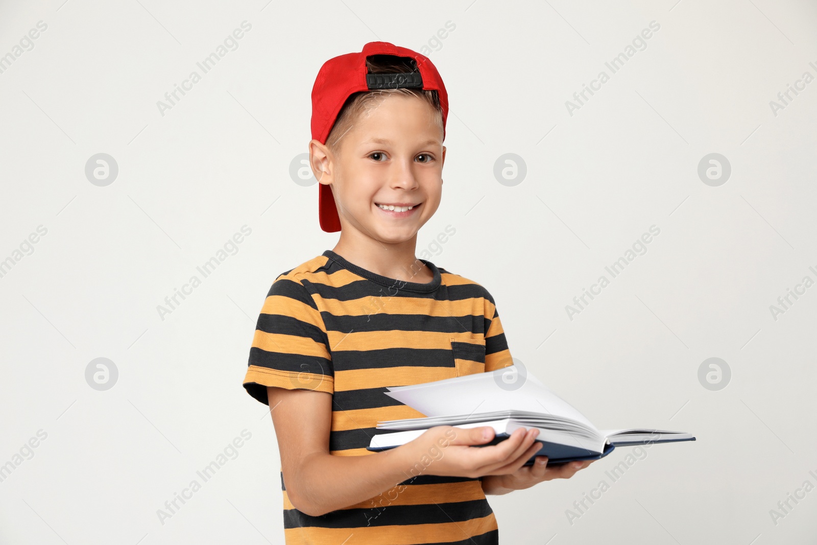 Photo of Portrait of cute little boy reading book on grey background