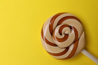 Photo of Delicious lollipop on yellow background, top view. Space for text