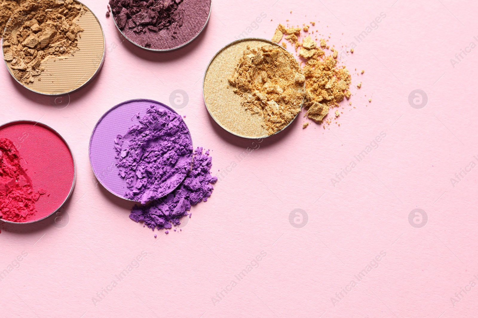 Photo of Different crushed eye shadows on pink background, flat lay. Space for text