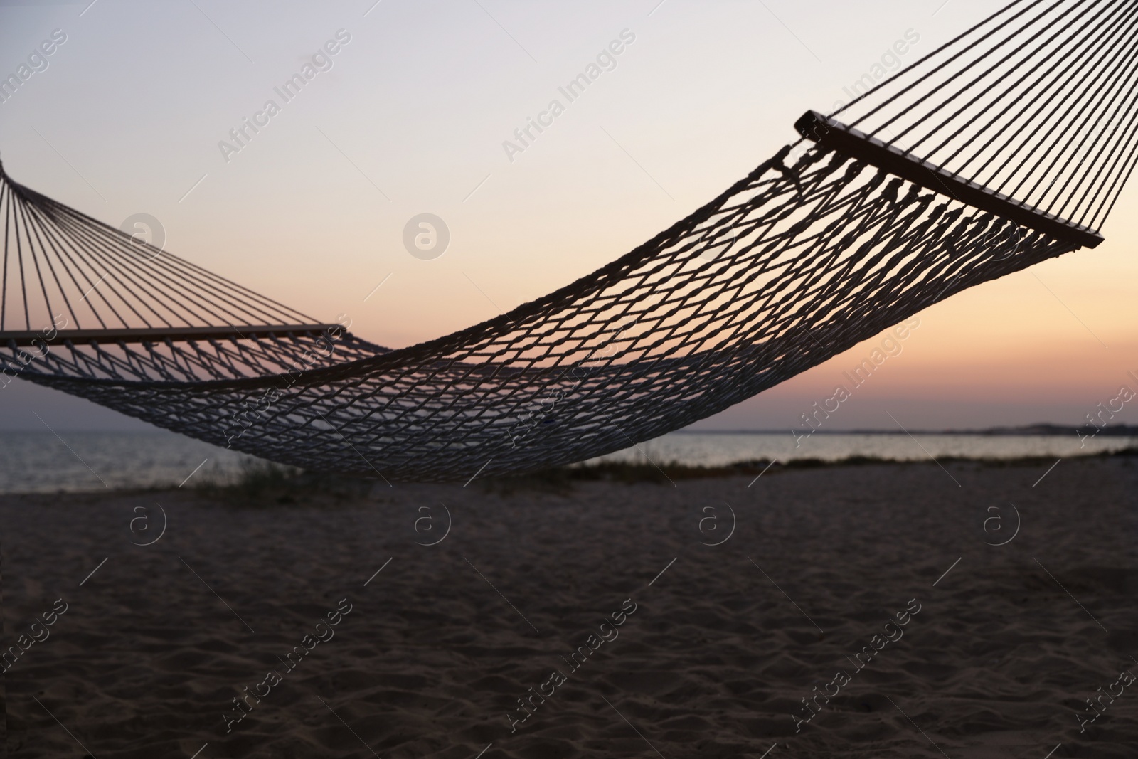 Photo of Empty hammock on beach at sunset. Time to relax