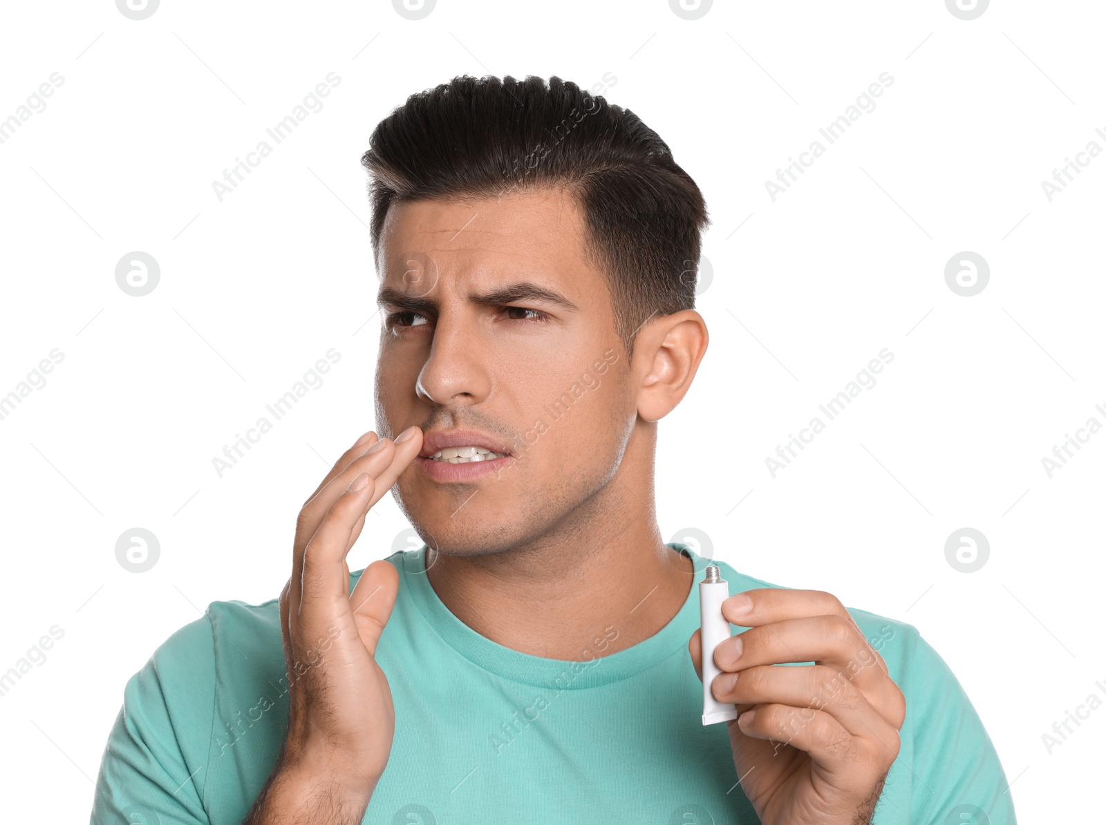 Photo of Emotional man with herpes applying cream on lips against white background