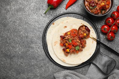 Photo of Tasty chili con carne with tortilla and ingredients on grey table, flat lay. Space for text