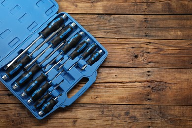 Photo of Set of screwdrivers in open toolbox on wooden table, top view. Space for text