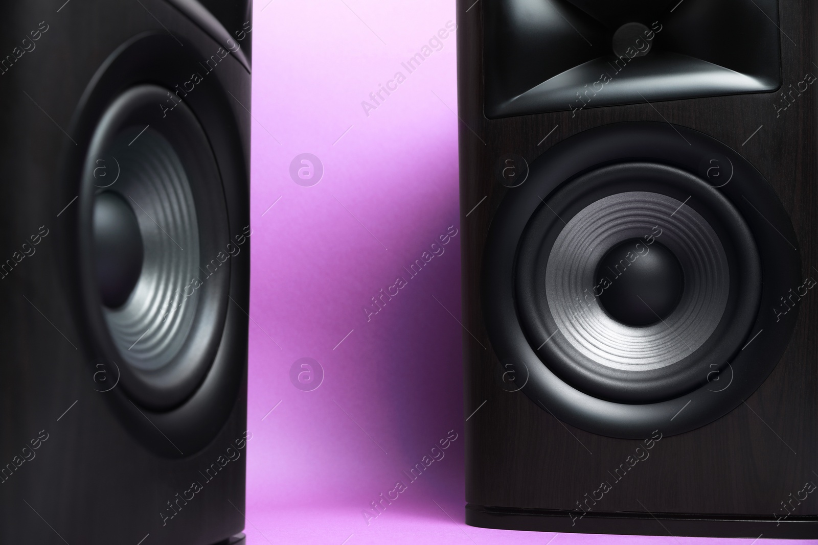 Photo of Wooden sound speakers on violet background, closeup