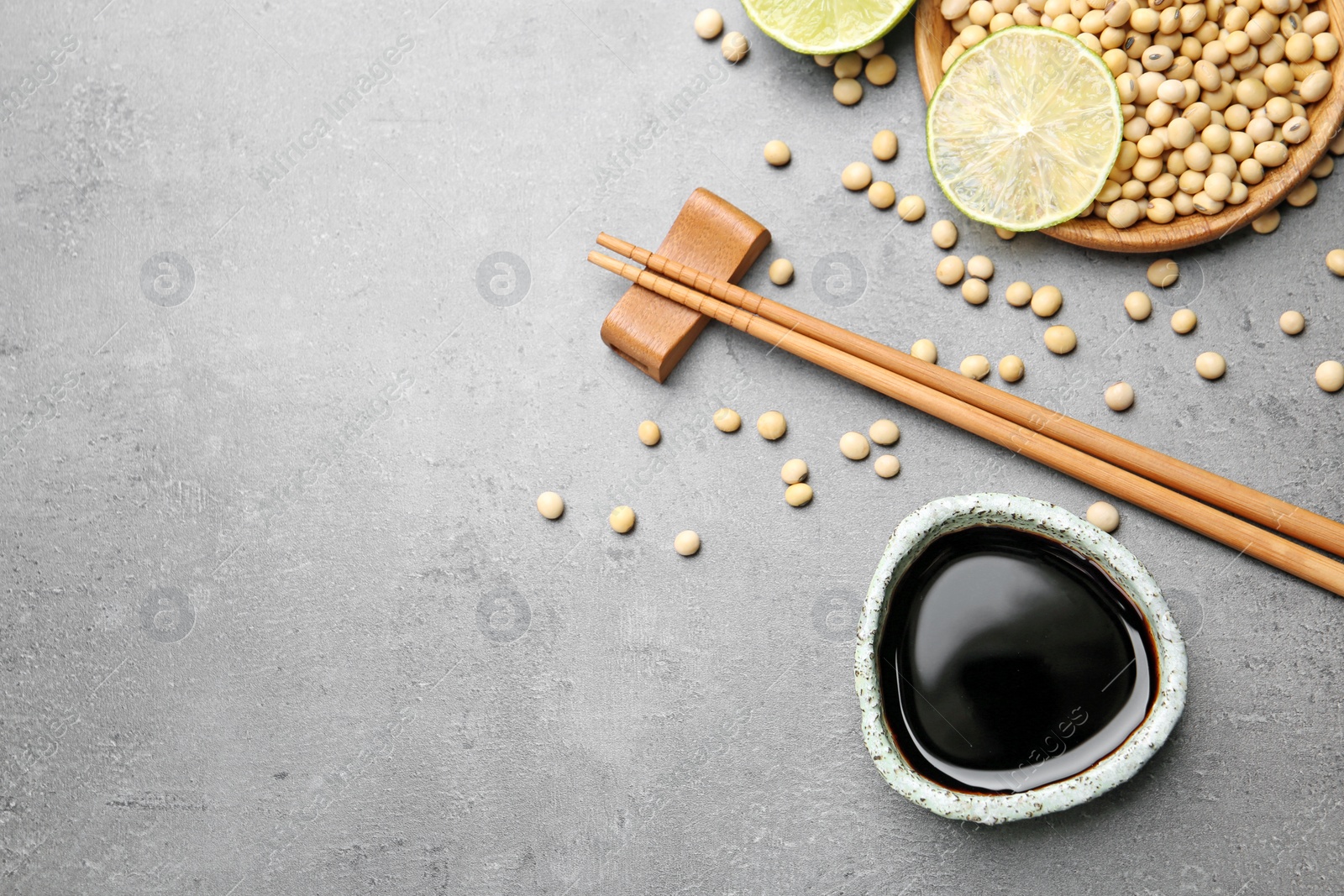 Photo of Flat lay composition with soy sauce and beans on grey table. Space for text