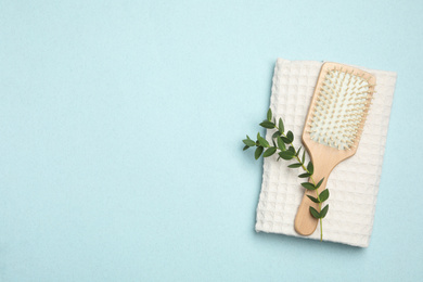 Photo of Modern paddle hair brush and plant on light background, flat lay. Space for text
