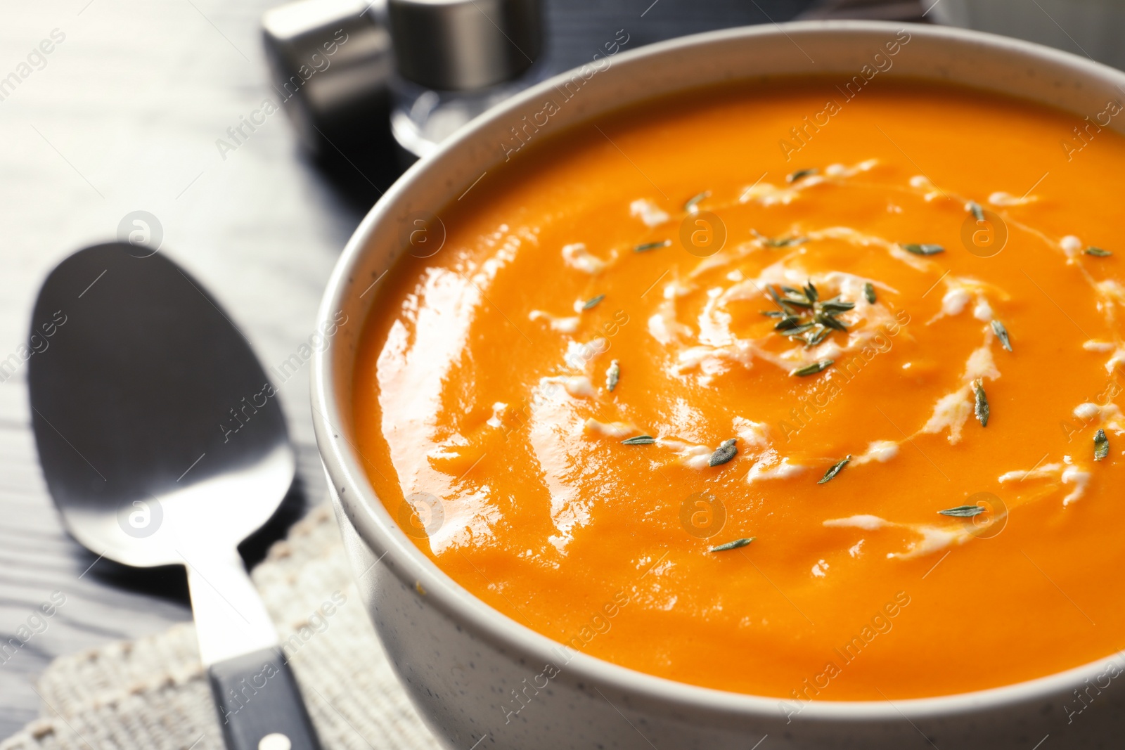 Photo of Delicious pumpkin cream soup in bowl on table, closeup