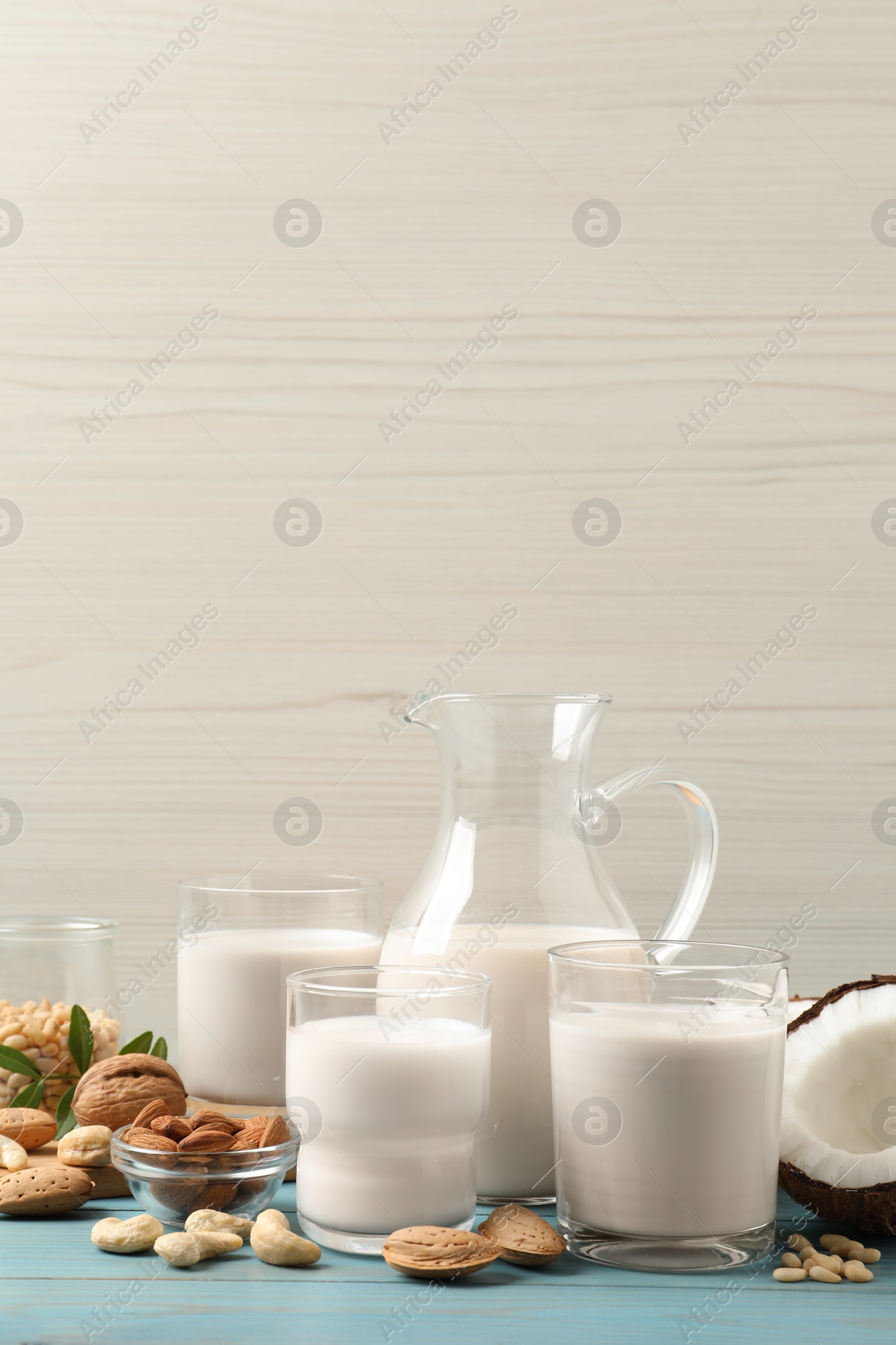 Photo of Different nut milks on light blue wooden table. Space for text