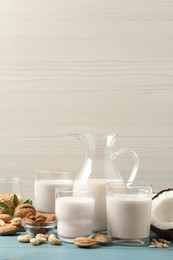 Photo of Different nut milks on light blue wooden table. Space for text