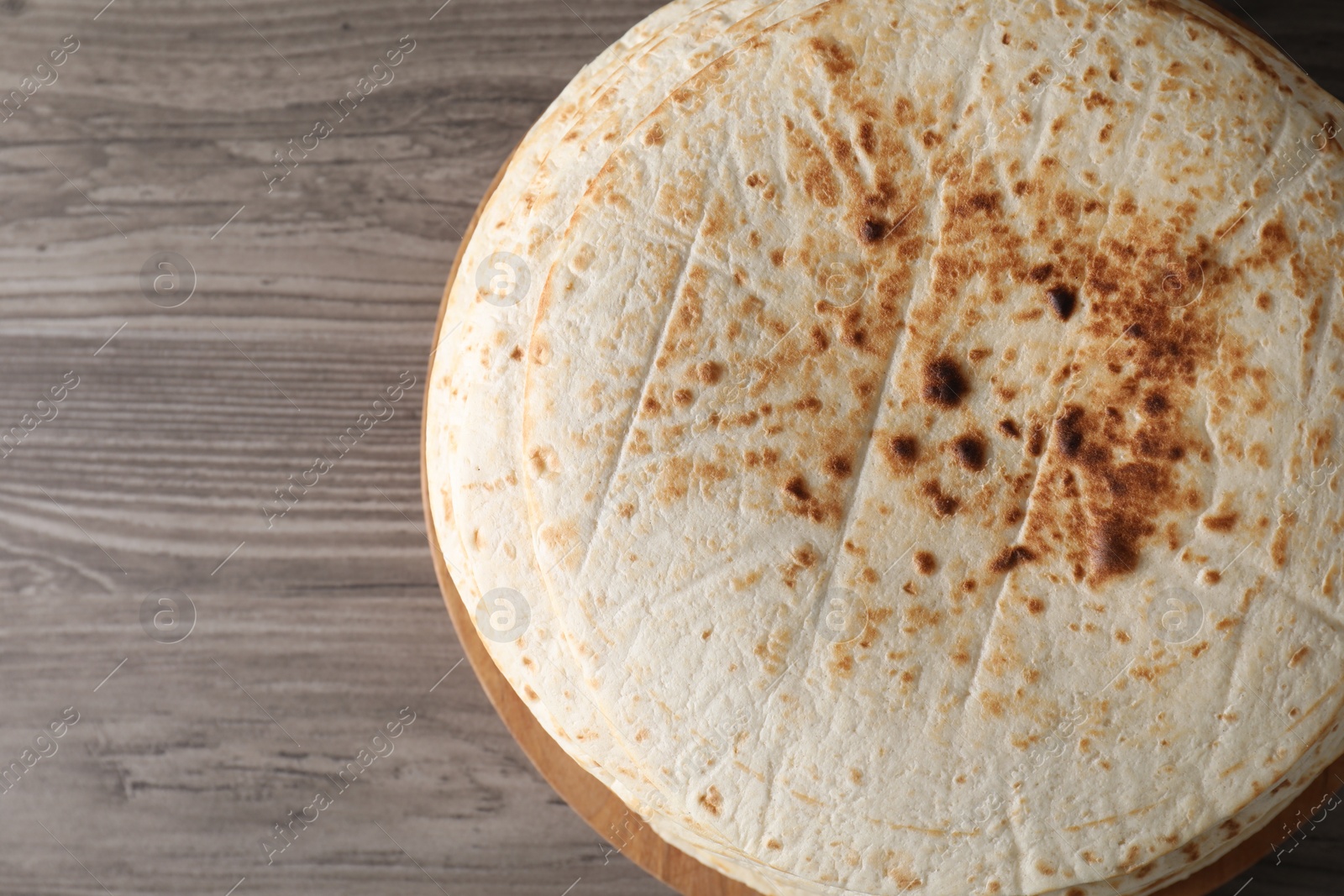 Photo of Many tasty homemade tortillas on wooden table, top view. Space for text